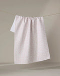 The Minimalist Blush tea towel by Teri the Butter, crafted from recycled materials, features a subtle pink botanical pattern and hangs neatly against a neutral background.