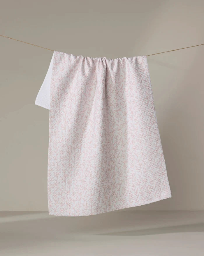The Minimalist Blush tea towel by Teri the Butter, crafted from recycled materials, features a subtle pink botanical pattern and hangs neatly against a neutral background.