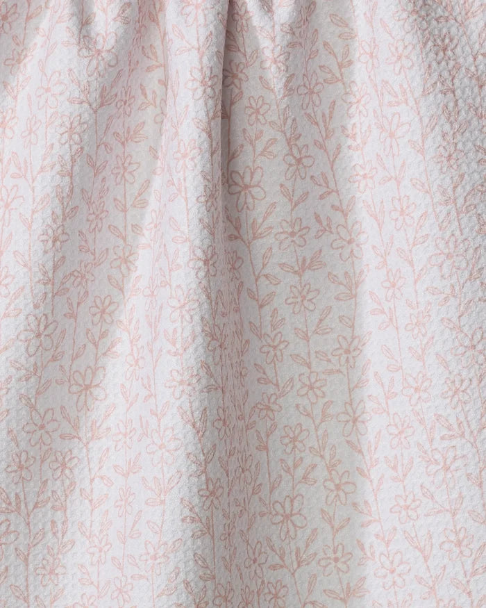 The Minimalist Blush tea towel by Teri the Butter features light pink fabric with a delicate floral pattern and thin stems. Quick-drying and softly gathered at the top, it’s textured and perfect for everyday use.