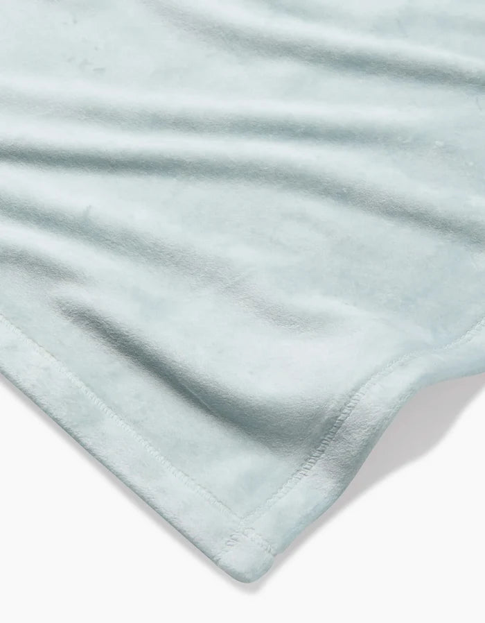 A close-up of the GEOMETRY Mint Drift Butter Blanket, made from post-consumer recycled materials with silky softness and neatly stitched edges, laid flat on a white background.