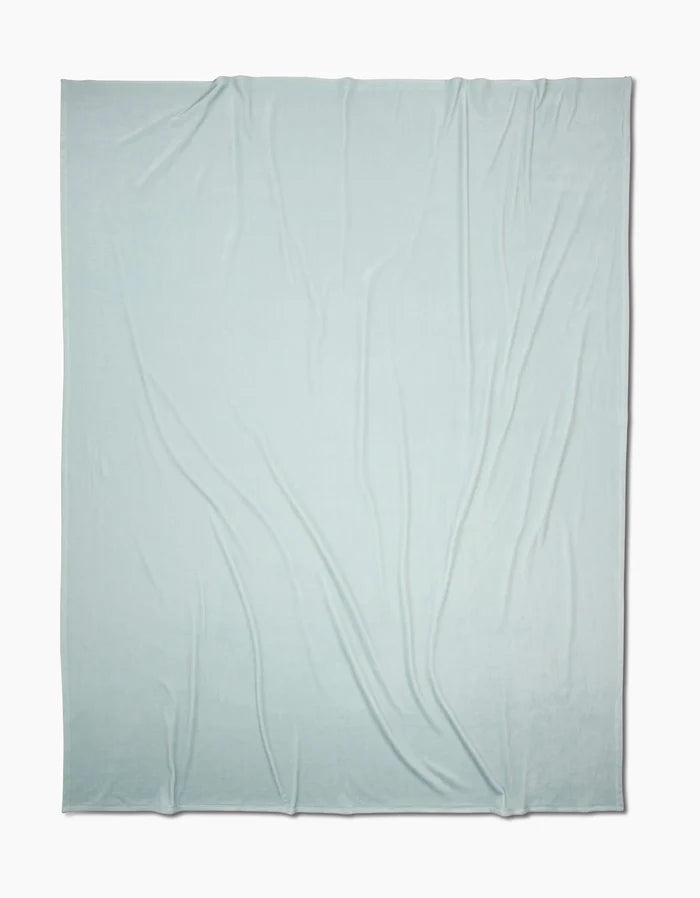 A large, Mint Drift Butter Blanket from GEOMETRY with silky softness and subtle wrinkles is spread out flat on a white background.
