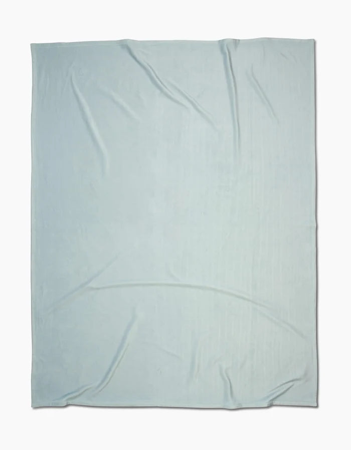 A Mint Drift Butter Blanket by GEOMETRY, featuring silky softness and subtle wrinkles, is spread out flat against a white background.