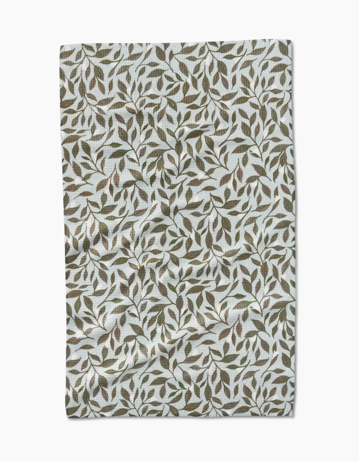 The Mint Leaves tea towel by Katie OShea features Geoweave fabric and a dense green and brown leaf pattern on white.