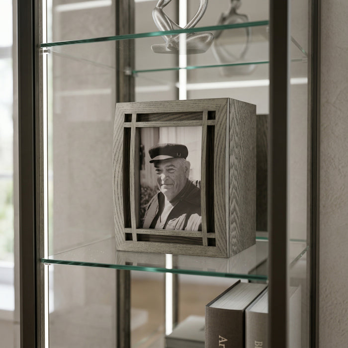 Wooden curved portrait urn with a black and white photo of an elderly man on a glass shelf.