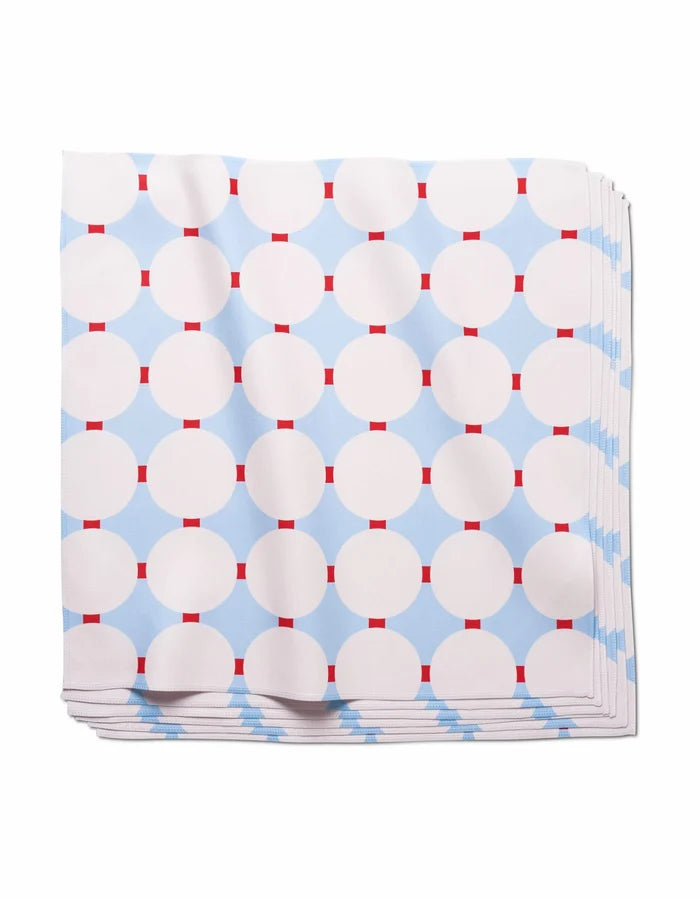 The Mist Blue Oasis dinner napkins by Happy Hemera feature a geometric pattern of white circles and red rectangles on a light blue background, crafted from soft Geosuede fabric for an elegant touch.