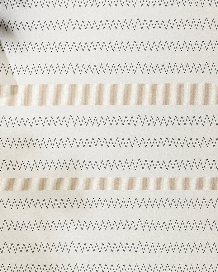 The Mod Zig Zag by Coit Creative features alternating rows of black zigzag lines and light beige vertical stripes on a white background, reminiscent of a recycled yoga towel. A shadow is visible in the top left corner.
