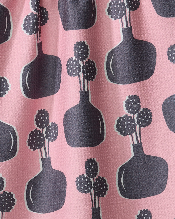 The "Modern Bouquet" kitchen towel by Lizzie Clark features pink recycled fabric with a textured surface and a repeating pattern of dark gray vases with round, polka-dot flowers, evenly spaced throughout.