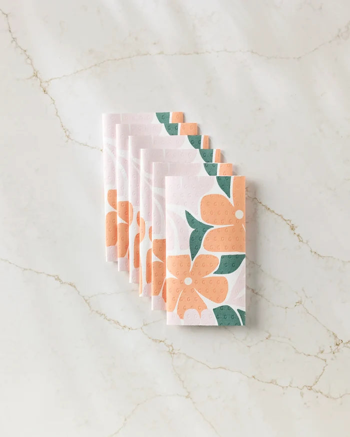 Six Modern Floral reusable paper towels by Lisa Nelson, each folded and featuring bold orange and green flower prints, are neatly arranged on a marble surface.