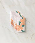 Six Modern Floral reusable paper towels by Lisa Nelson, each folded and featuring bold orange and green flower prints, are neatly arranged on a marble surface.