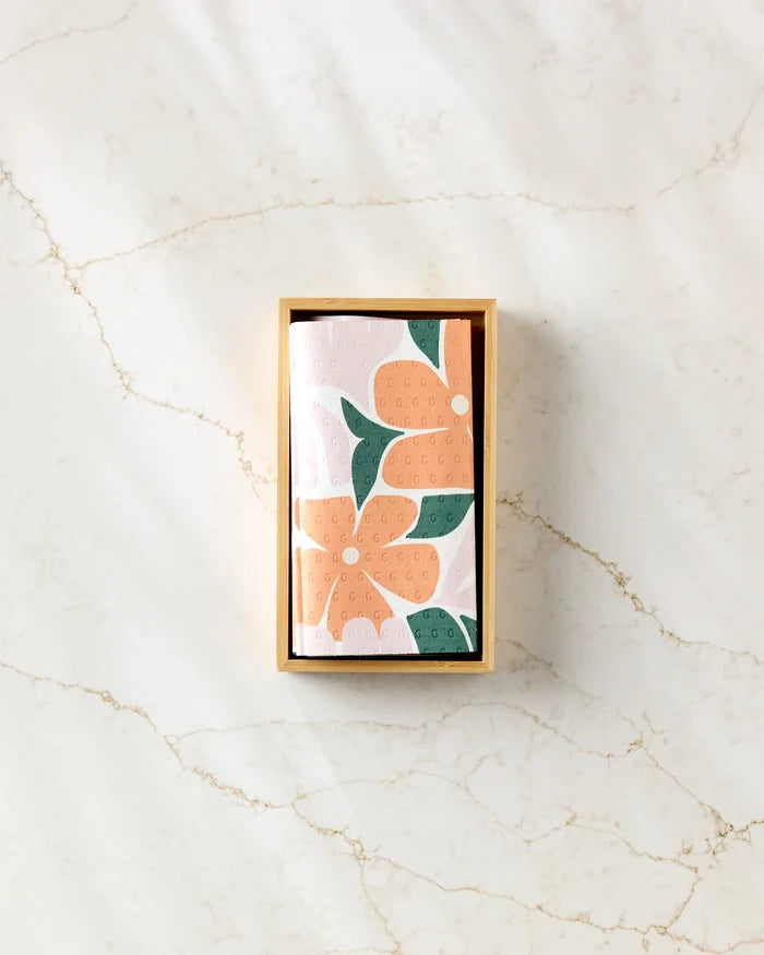 A rectangular "Modern Floral" box by Lisa Nelson sits on marble, holding orange, green, and white floral cloths—ideal as reusable paper towels for an eco-friendly home.