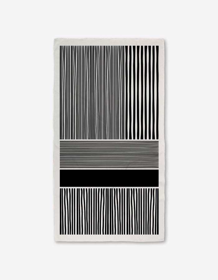 The Modern Form towel by GEOMETRY features Geoweave technology with black and white vertical stripes on the top and bottom, and abstract horizontal lines of varying thicknesses and shades in the middle for a modern look.