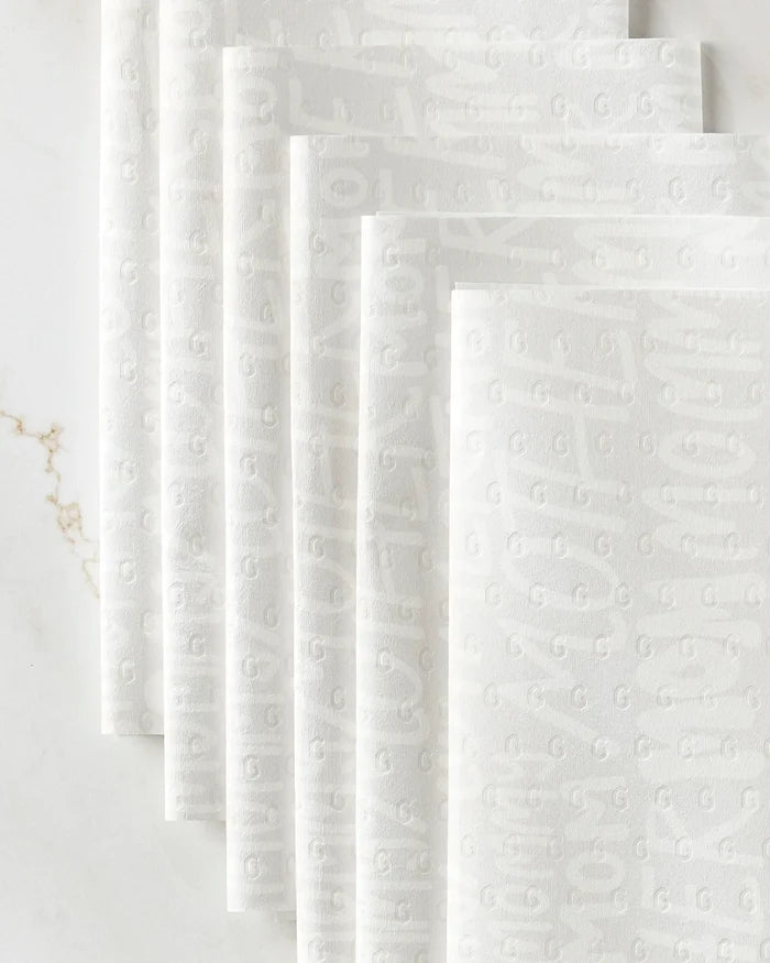 GEOMETRY's Mom reusable paper towels, featuring a subtle embossed pattern, are fanned out on a white marble surface with delicate veining.