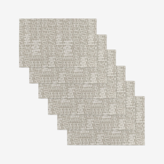 Seven beige rectangular GEOMETRY Mom placemats featuring a white abstract pattern, made from eco-friendly materials, are arranged in a staggered, overlapping layout on a white background.