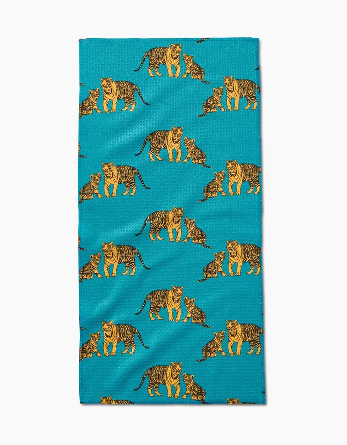 The Mommy and Me Bar Towel by Sarah Holden showcases orange and black illustrated tigers and cubs in playful poses on soft Geoweave fabric with a turquoise background.
