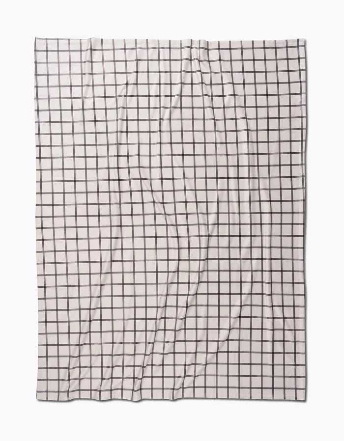 The Moon by Geometry is a white fabric featuring a black grid of evenly spaced squares, shown flat with natural wrinkles and folds, offering silky softness like a Butter Blanket.