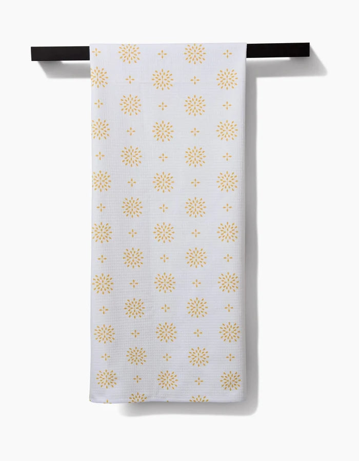 The Danelys Sidron Morning Petals bath towel, featuring a repeating yellow sunburst pattern and Geoweave technology for superior absorbency, hangs neatly on a black towel bar against a plain white background.