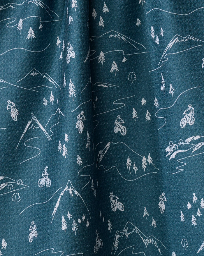 Coit Creative's "Mountain Biking" is a blue recycled kitchen towel with a white line art pattern of mountains, trees, and cyclists throughout the design.