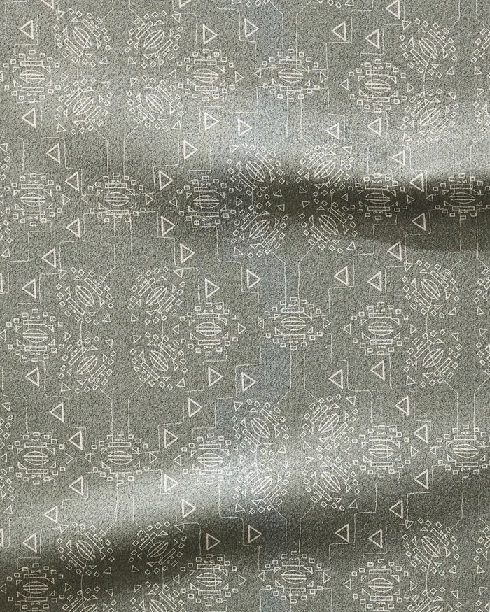 The Mountain Bloom fitness towel by Ash Cascade features gray fabric with a subtle sheen and a repeating pattern of white circles, triangles, and rectangles. Ultra-absorbent with gentle horizontal folds.