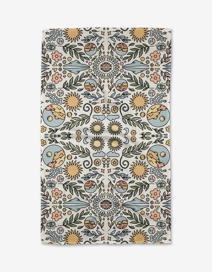 The Mountain Mosaic rug by Graphics and Grain features a symmetrical sunflower, leaf, and swirl motif in blue and yellow on white, crafted from recycled materials for a look inspired by decorative tea towels.