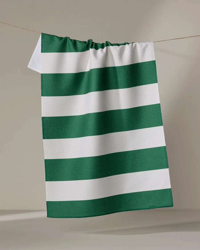 The Modern Dad’s “Mr. Day On The Green” kitchen towel, featuring green and white horizontal stripes, hangs on a string against a plain, light-colored background.