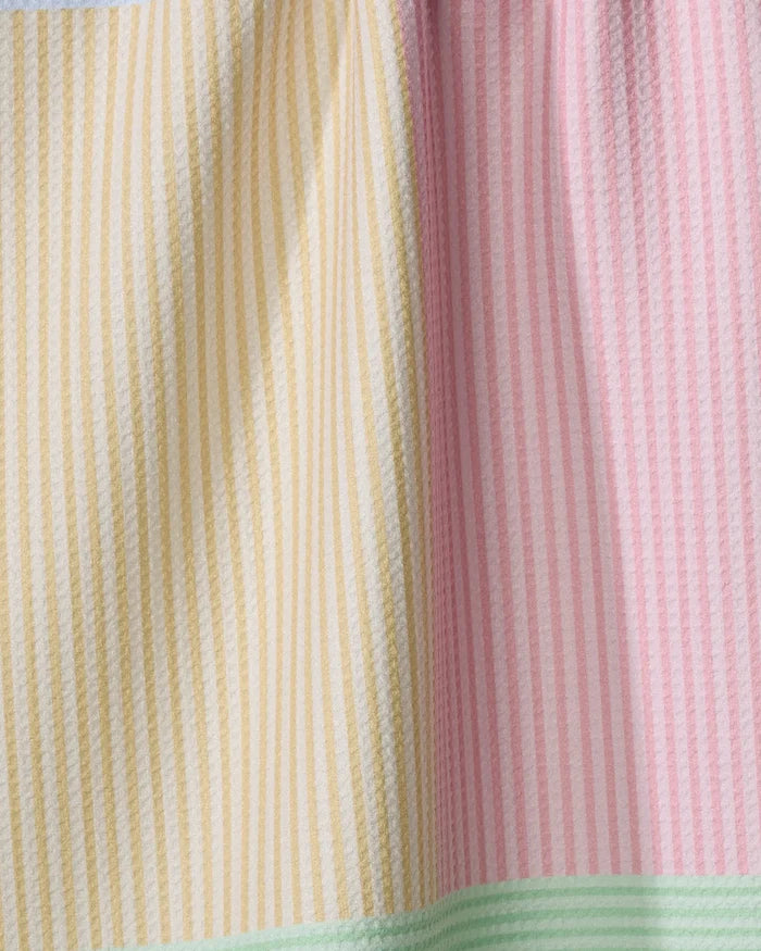 A close-up of The Modern Dad’s Mr. Fun Stripes tea towel shows vertical yellow and pink stripes with a seam, plus a mint green stripe at the bottom. This ultra-absorbent, soft towel has a textured look and is crafted from recycled materials.