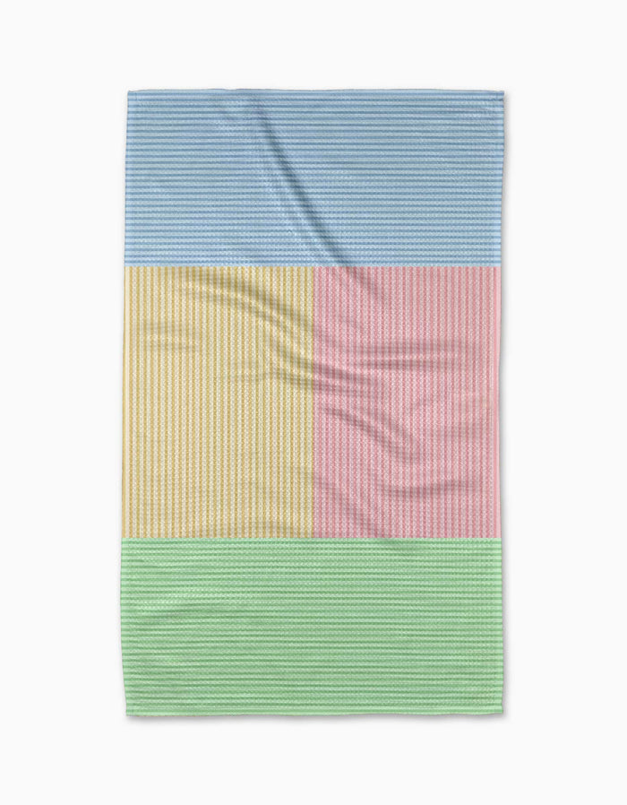 The Modern Dad’s Mr. Fun Stripes tea towel features Geoweave fabric with four rectangular color blocks—blue, yellow, pink, and green—each adorned with thin white stripes on a white background.