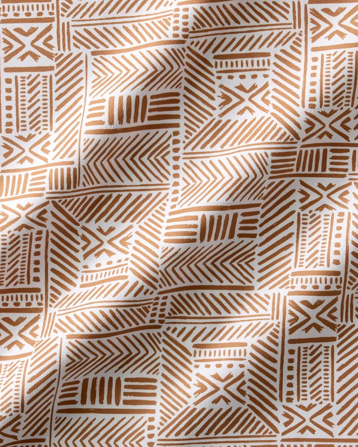 The Hufton Studio "Mud Cloth Natural" dinner napkin set features a brown geometric tribal pattern on white fabric with soft folds, ideal as eco-friendly napkins for sustainable, stylish dining.