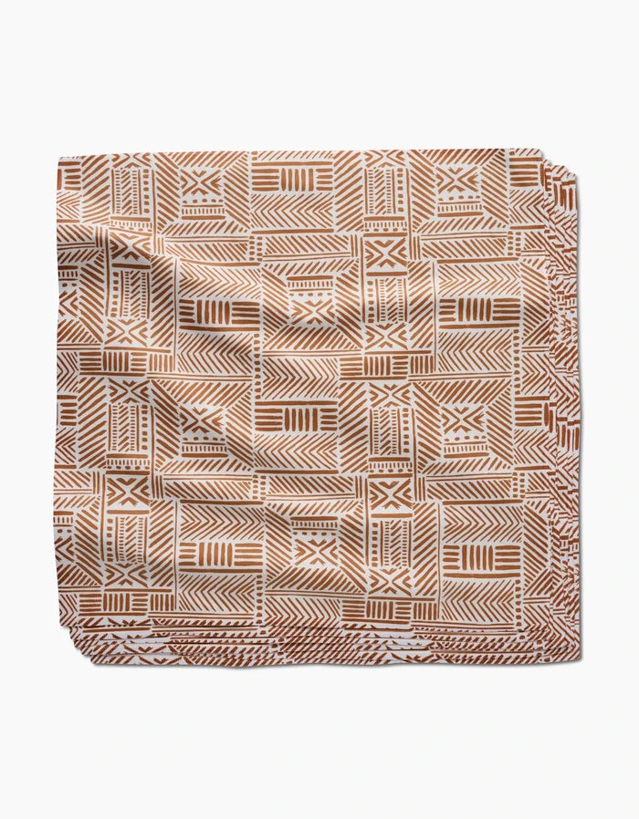 The Mud Cloth Natural Dinner Napkin Set by Hufton Studio features a brown and white geometric pattern with lines, triangles, and squares on soft, eco-friendly Geosuede fabric.