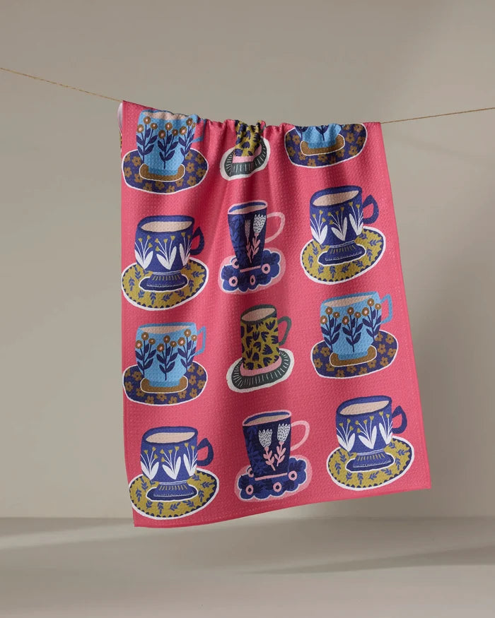 The Mug Set by Cottonflower Studio features a vibrant pattern of illustrated teacups and saucers with unique floral designs, inspired by colorful tea towels made from recycled materials.