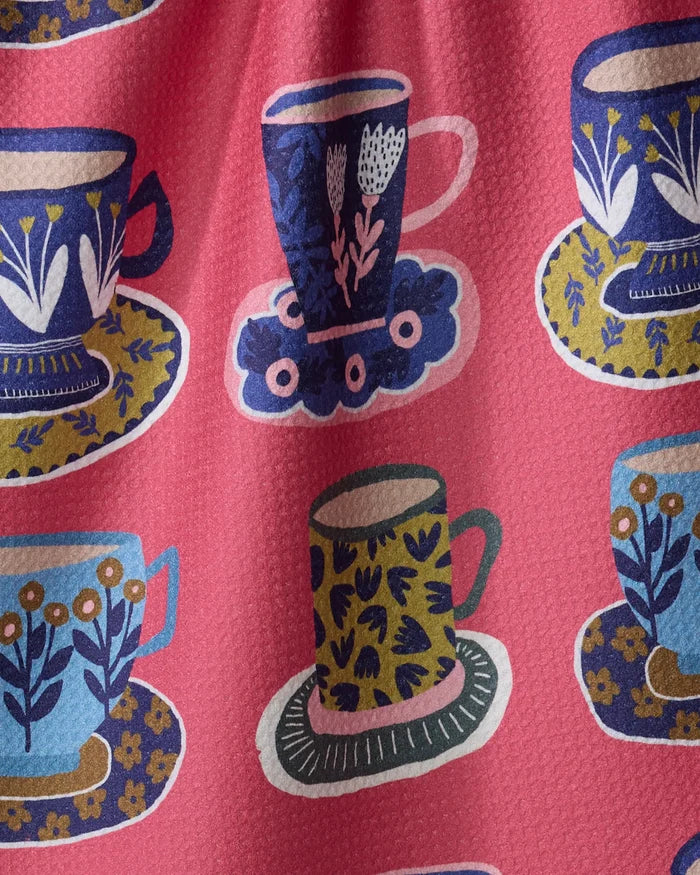 The Mug Set by Cottonflower Studio features a pink textured fabric made from recycled materials, with a repeating pattern of blue, yellow, and green teacups and saucers adorned with floral designs.