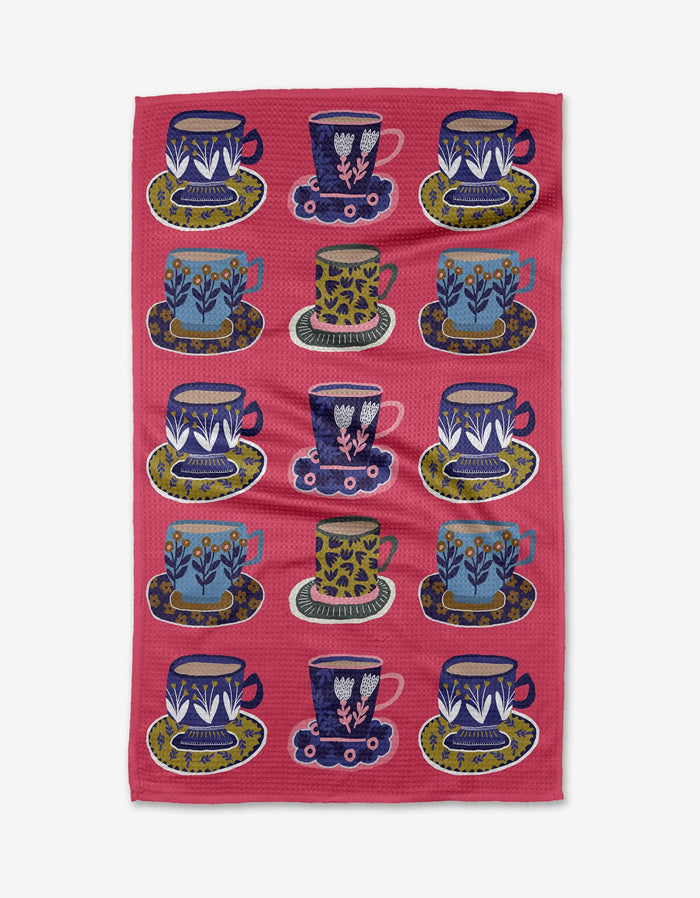 The Cottonflower Studio Mug Set features twelve mugs with matching saucers, each in a unique floral or geometric pattern of blue, green, white, pink, and yellow, arranged in a colorful grid.