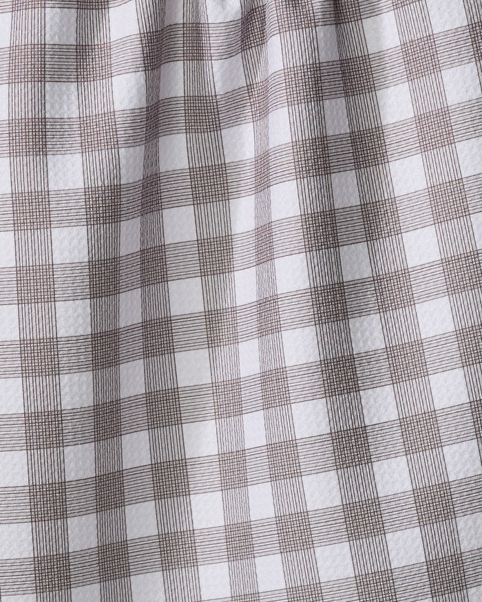 A close-up of The Buy Guide’s Multi Gingham - Chocolate recycled kitchen towel, featuring a white base with a brown plaid grid and slightly textured, gathered fabric near the top.