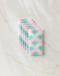 Six Nalin reusable paper towels by Amy MacCready, featuring a pastel arch pattern in pink, teal, and white, are neatly folded and set on a light marble surface.