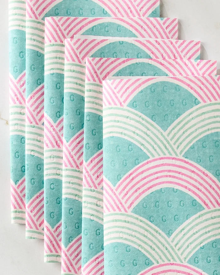 Five eco-friendly Nalin paper towels by Amy MacCready, featuring a retro geometric pattern of teal, pink, and white scallops and lines, are neatly stacked on a light surface.