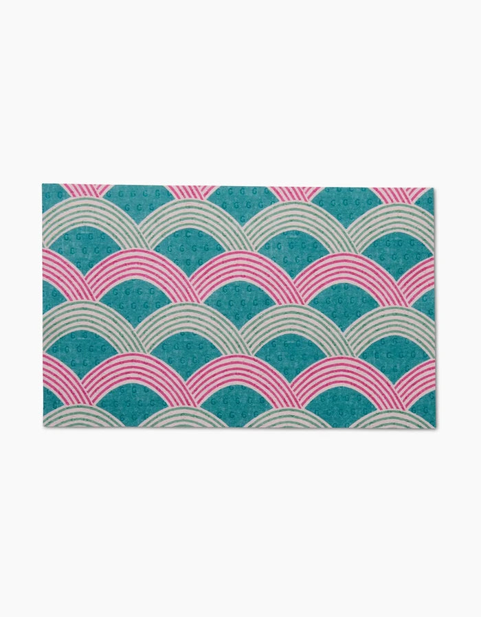 The Nalin mat by Amy MacCready features overlapping semi-circles in teal, pink, and white with striped lines and dot textures on a white background—crafted from recycled materials for an eco-friendly choice.