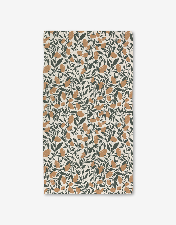 The Naomi bath towel by Charlie Rowan Designs features an orange floral and dark green leaf pattern on cream. Made with Geoweave technology, it offers a vintage botanical look plus modern absorbency and function.