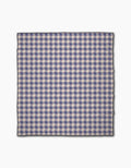The Geometry Nautical Gingham is a square beach blanket with a blue, white, and light pink checkered pattern, thin black border, and made of quick-drying recycled materials, shown flat on a white background.