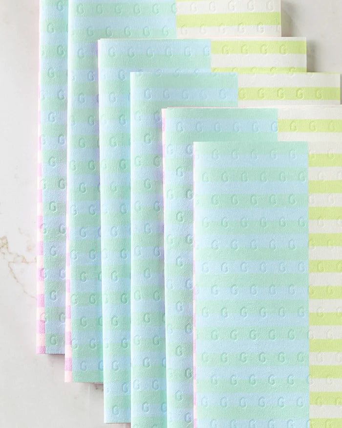 Neon Nights by GEOMETRY features pastel, textured sheets with a subtle G pattern in blue, green, pink, and striped designs—an eco-friendly paper towel alternative stylishly layered on a light surface.