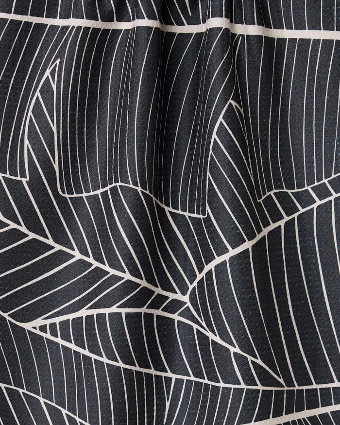 Close-up of GEOMETRYs Neutral Palms: black fabric with bold white geometric palm patterns. The gathered top forms soft pleats and shadows, creating an elegant, modern look.
