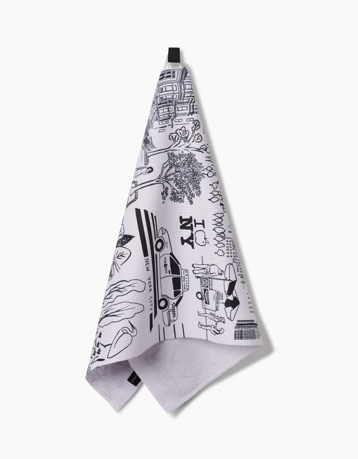 The Elisabeth Wing New York kitchen towel features ultra-absorbent Geoweave fabric and black line drawings of NYC icons like a taxi and “I ♥ NY”; it hangs from a black loop against a white background.