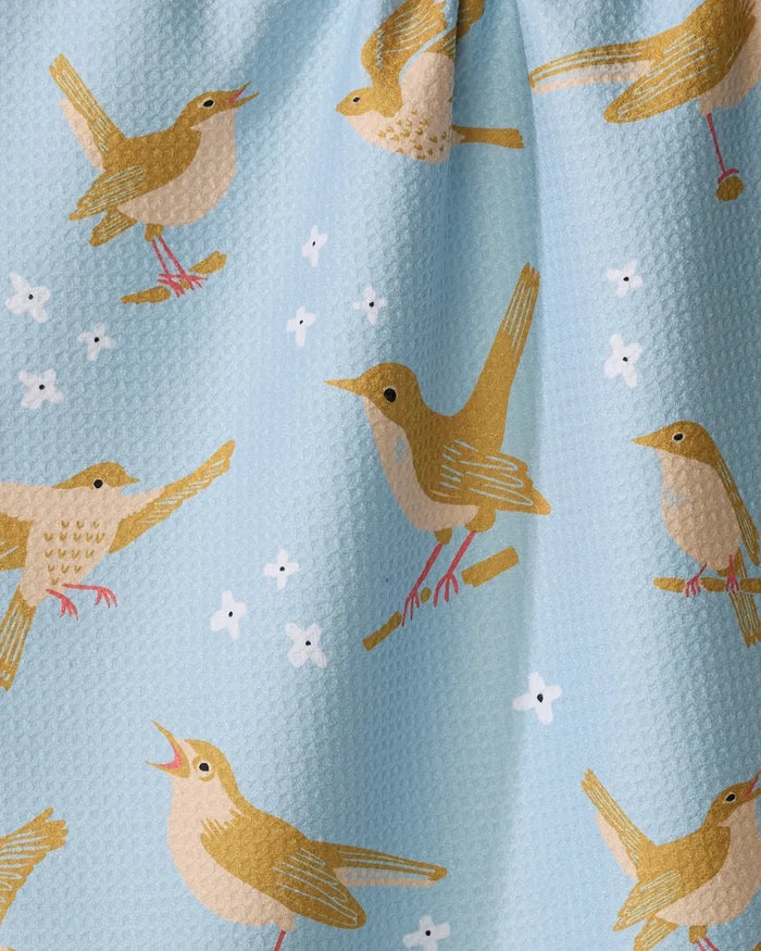 “Nightingales” by Elisabeth Wing features yellow and brown birds perched on branches, singing on a light blue textured background with white flower accents—perfect for an eco-friendly kitchen towel.