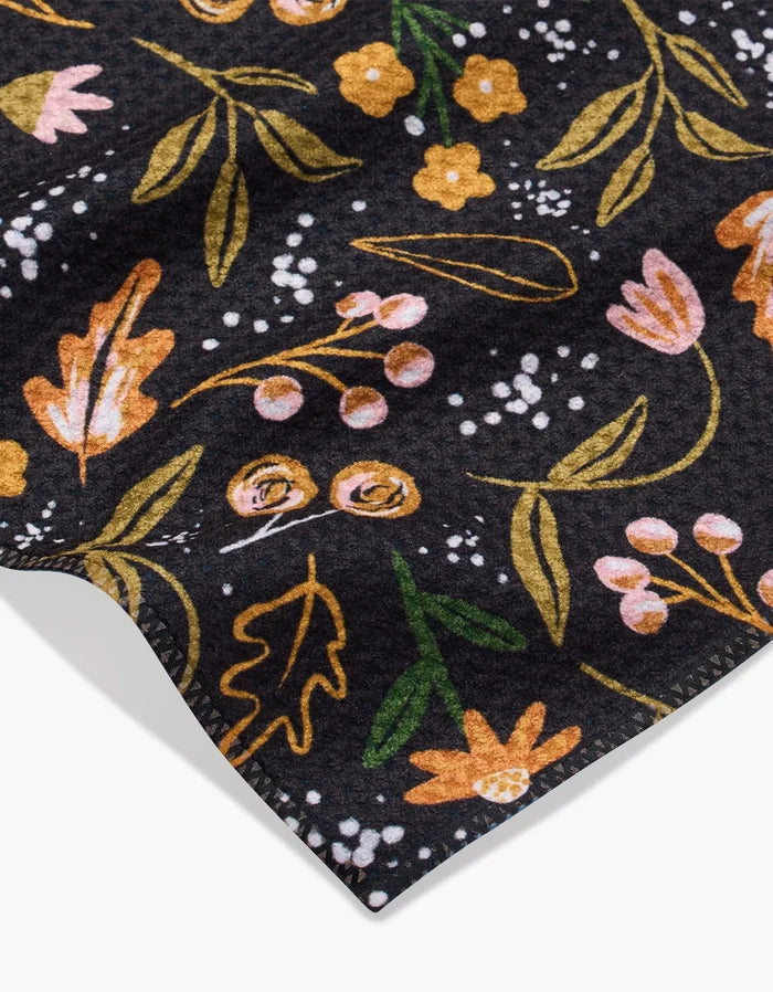 A close-up of Megan Roys Nighttime Botanical shows dark Geoweave fabric with yellow, pink, and orange floral patterns, green leaves, small white accents, and neatly stitched edges.