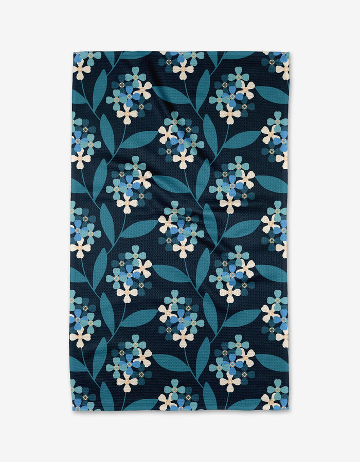 Nighttime Florals by Blissful Flamingo is a rectangular Geoweave fabric with an ultra-absorbent, dense, symmetrical pattern of light blue and white flowers with green leaves on a dark blue background.