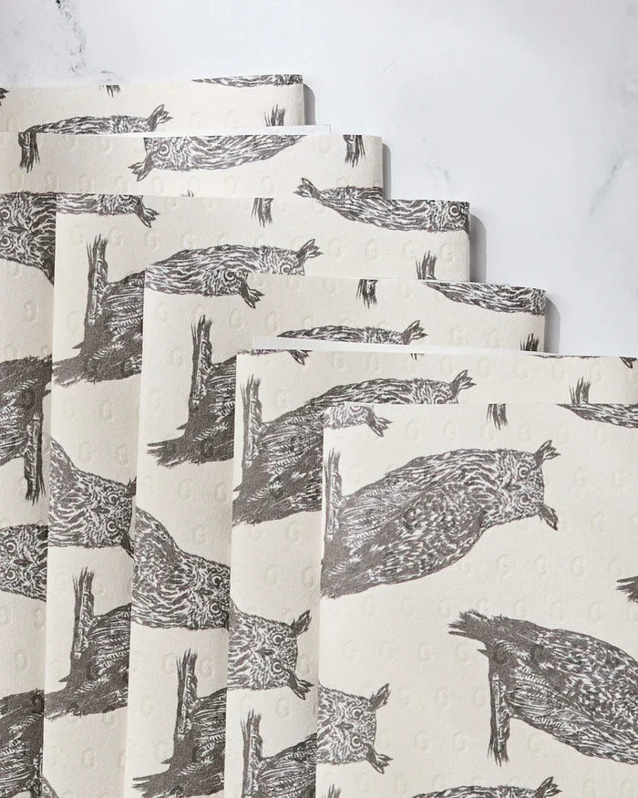 Five sheets of Geometrys Nocturne reusable paper towels, each featuring detailed brown owl sketches on cream, are stacked horizontally on a white marble surface.