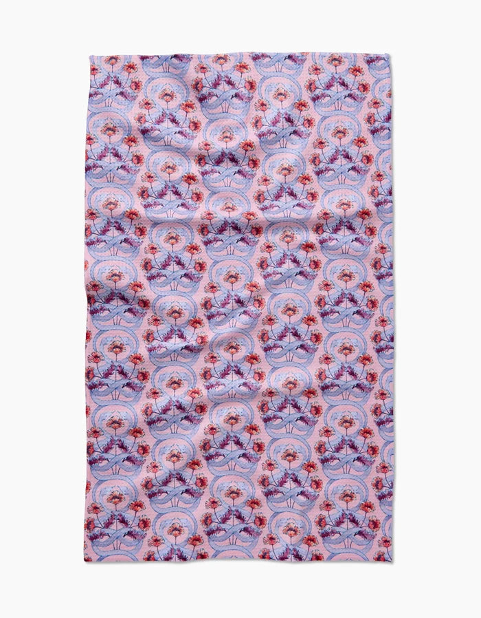 The Nouveau Snake by Maayan Alper-Swan is a rectangular Geoweave fabric featuring a symmetrical, intricate design of red and purple flowers with decorative shapes on a light pink background. Ultra-absorbent and laid flat.