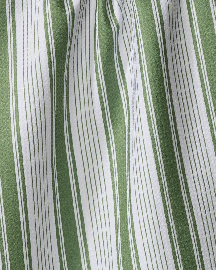 A close-up of Aubrey Fairchild’s “Of the Same Stripe” tea towel, made from recycled materials, shows vertical green and white stripes in varying thicknesses with soft folds and shadows accentuating its textured fabric.