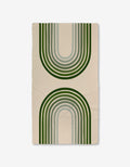 The Olive Arches rug by GEOMETRY is a beige rectangle made with Geoweave technology, showcasing two large green and gray arches—one upward, one downward—for a modern, symmetrical look.