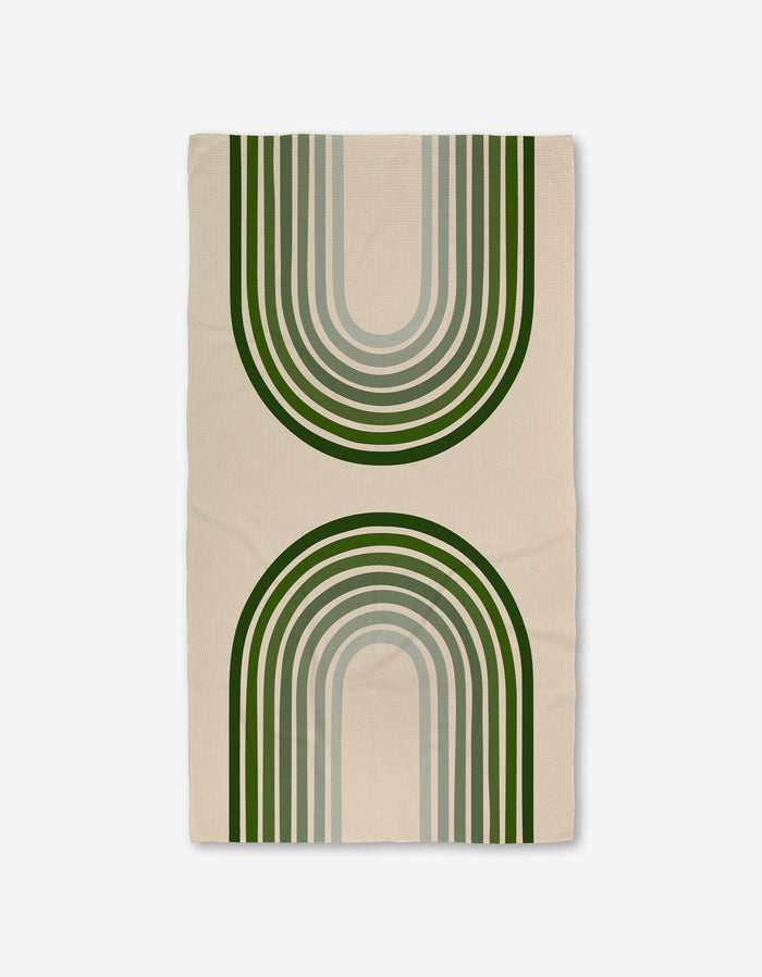 The Olive Arches rug by GEOMETRY is a beige rectangle made with Geoweave technology, showcasing two large green and gray arches—one upward, one downward—for a modern, symmetrical look.