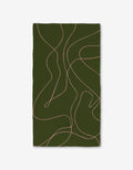 The GEOMETRY Olive Martini is a rectangular dark green blanket with thin, wavy light pink lines. Its made from ultra-absorbent post-consumer recycled materials and shown against a plain white background.