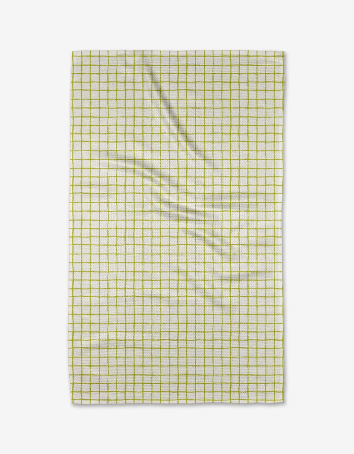 The On the Lawn tea towel by Kayla Ann is a rectangular, white kitchen towel featuring a grid of thin yellow lines. Absorbent and lightly creased, it’s shown flat against a white background.
